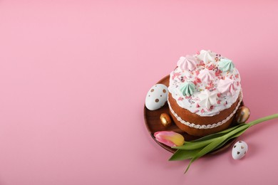 Photo of Traditional Easter cake with meringues, candle, decorated eggs and tulip on pink background. Space for text