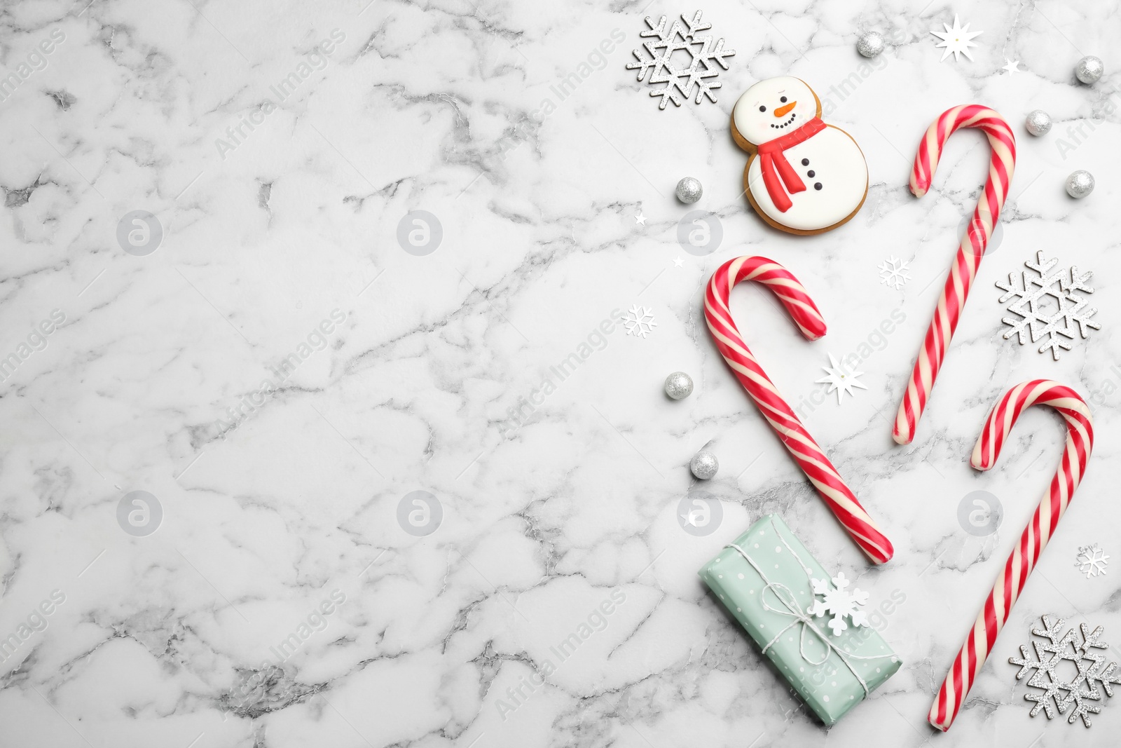 Photo of Flat lay composition with candy canes and Christmas decor on white marble table