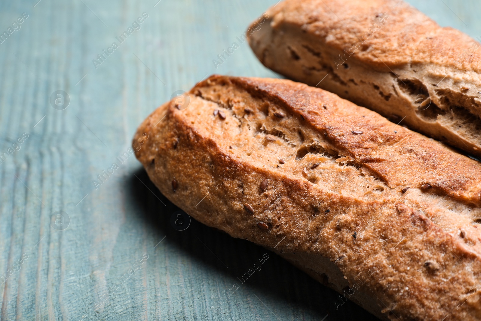 Photo of Tasty buckwheat baguettes on light blue wooden table, closeup