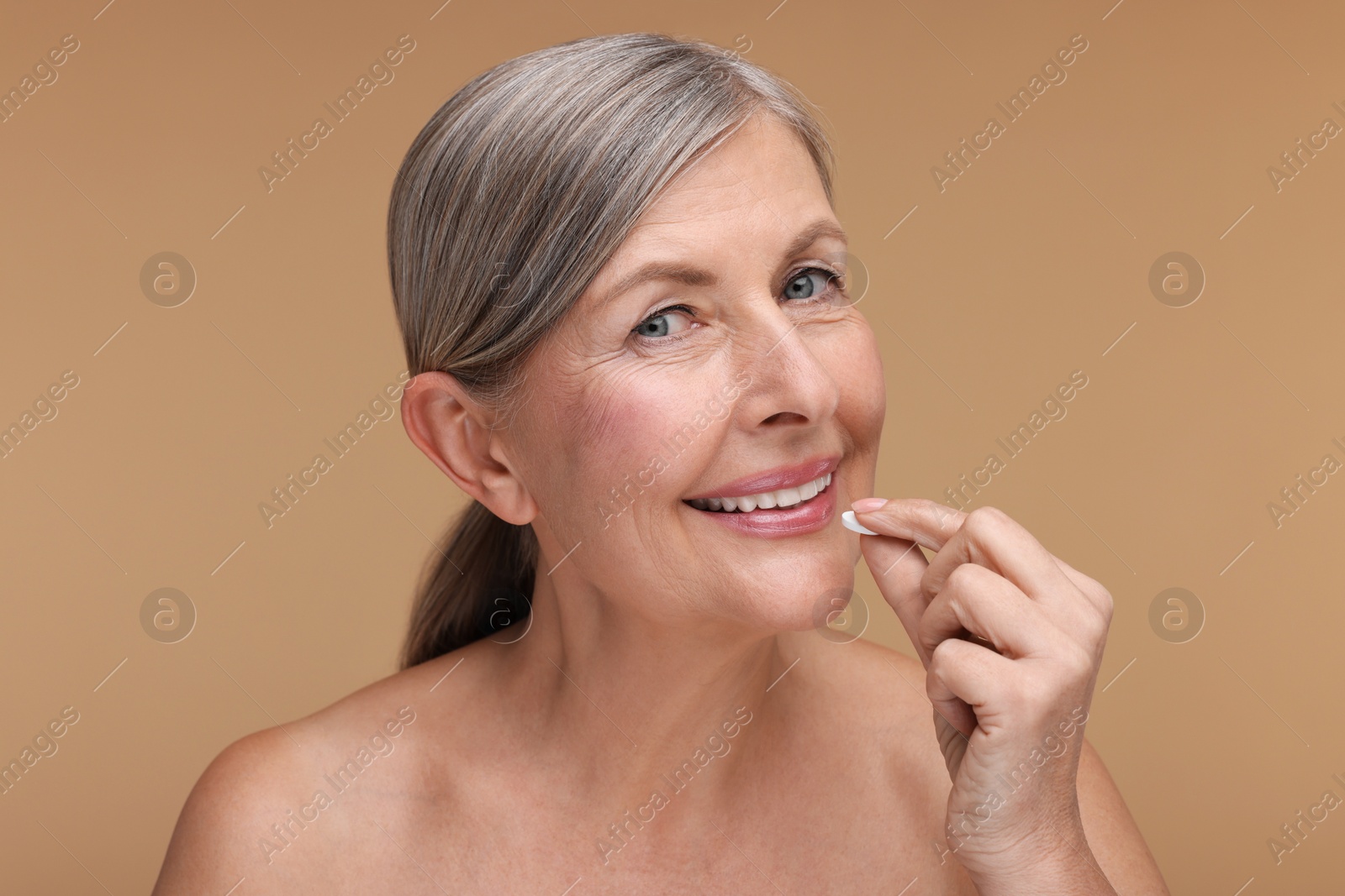 Photo of Beautiful woman taking vitamin pill on beige background