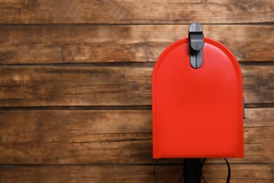 Photo of Closed red letter box against wooden background. Space for text