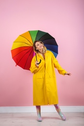 Woman with rainbow umbrella near color wall