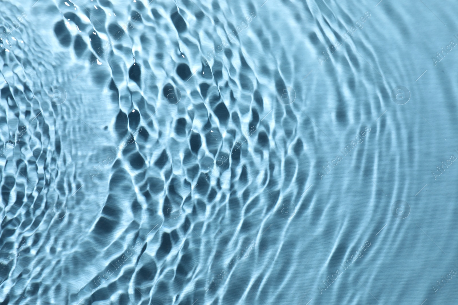 Photo of Rippled surface of clear water on light blue background, top view