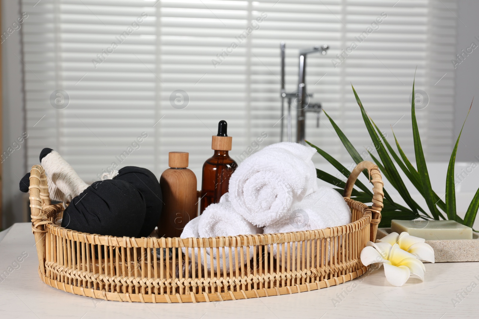 Photo of Beautiful composition with different spa products, flowers and green leaves on white wooden table in bathroom, space for text