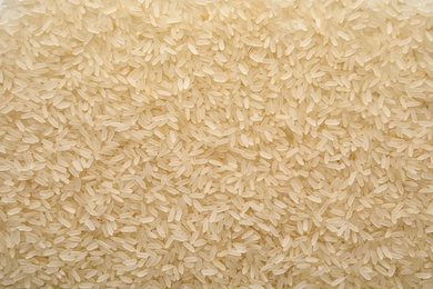 Photo of Pile of uncooked rice as background, top view