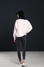 Photo of Young woman in sweater at black wall. Mock up for design