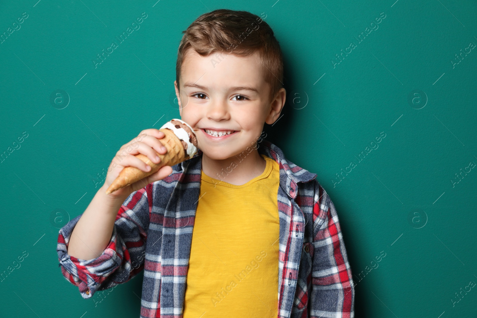 Photo of Adorable little boy with delicious ice cream against color background