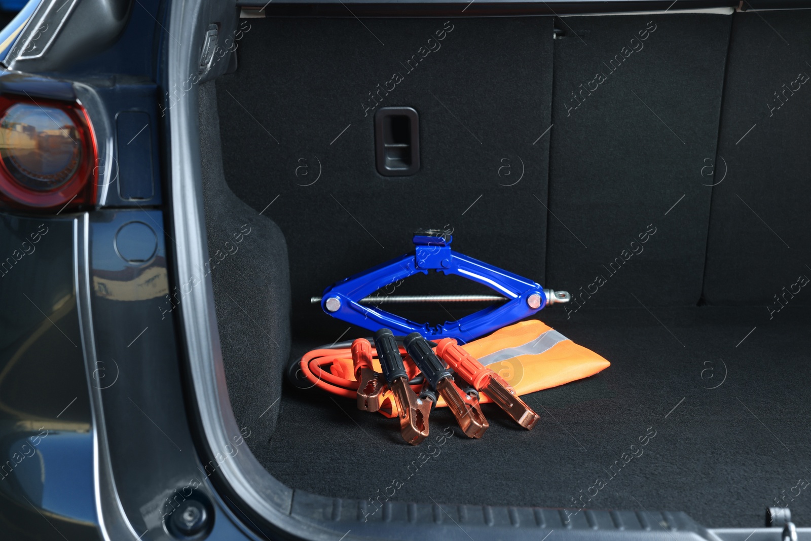 Photo of Scissor jack, life vest and battery jumper cables in trunk. Car safety equipment