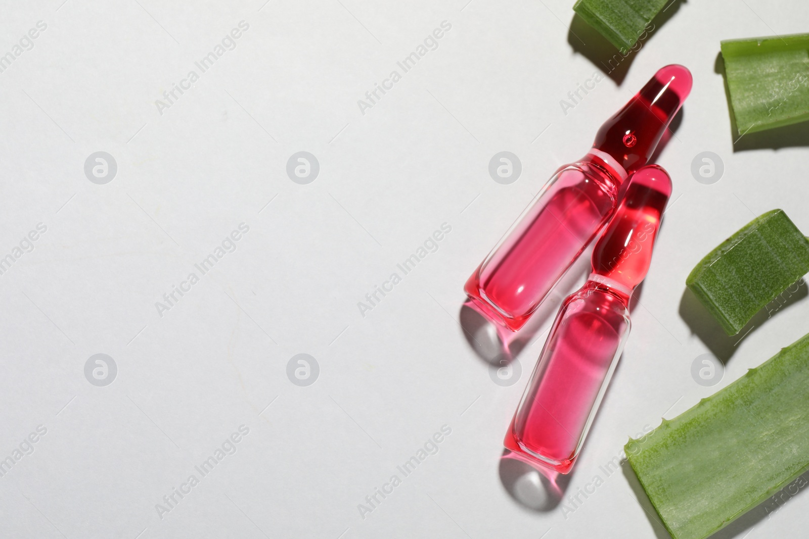 Photo of Pharmaceutical ampoules with medication and aloe leaves on light background, flat lay. Space for text