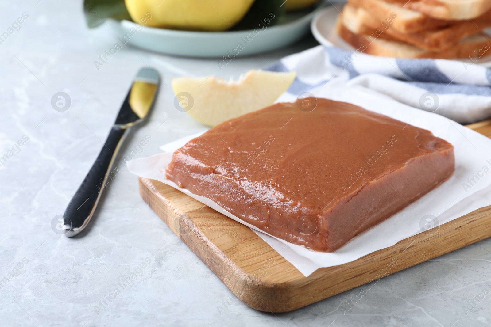 Photo of Wooden board with fresh quince paste on light grey marble table