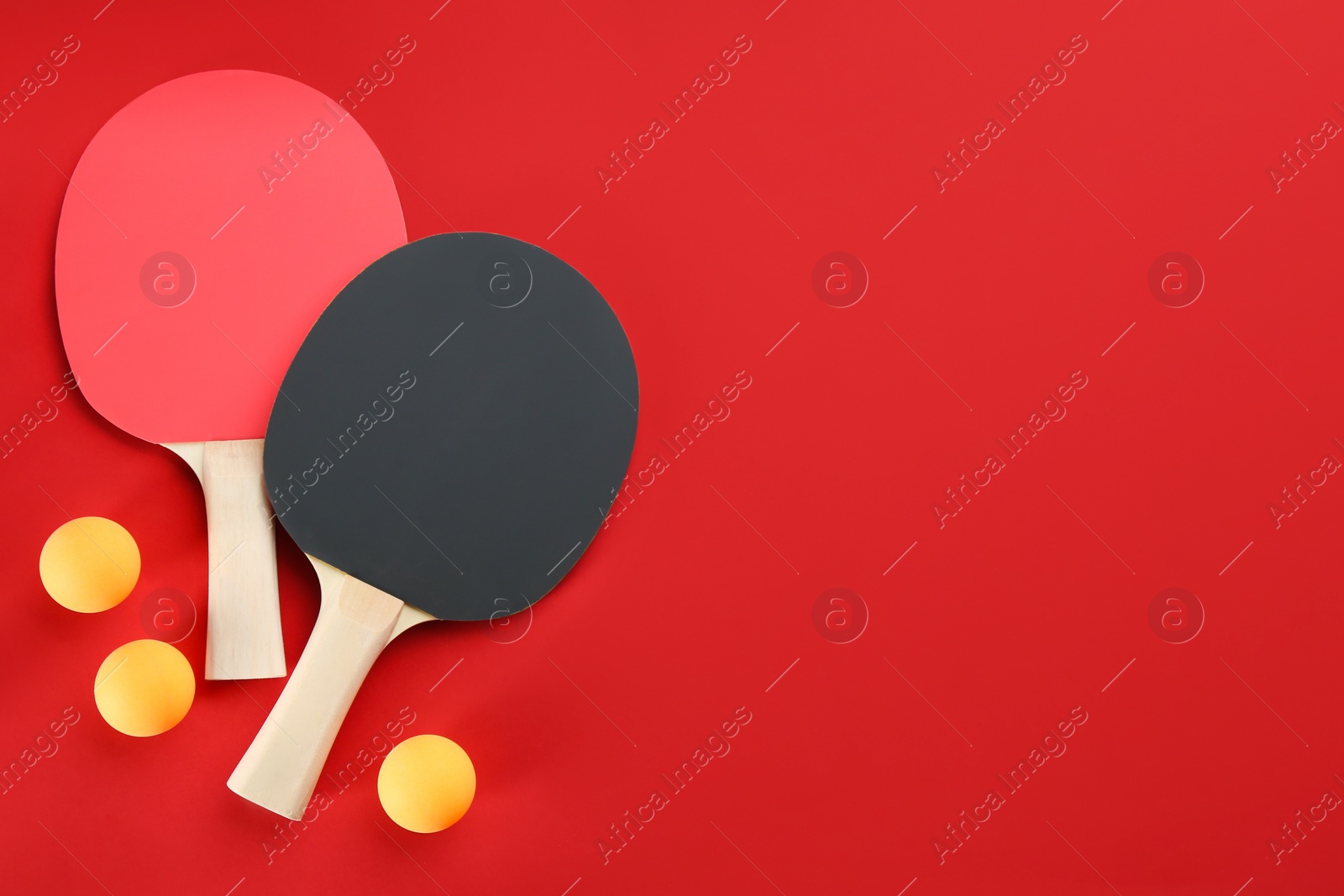 Photo of Ping pong rackets and balls on red background, flat lay. SPace for text