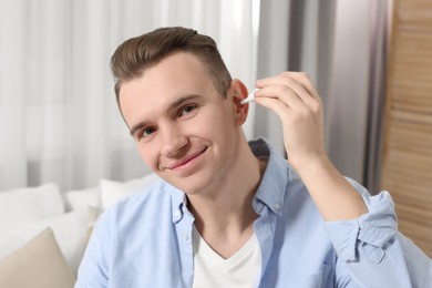Young man using ear drops at home