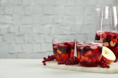 Photo of Delicious Red Sangria and ingredients on white wooden table, space for text