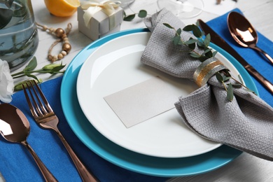 Elegant festive table setting with blank card on light background, closeup