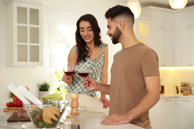 Lovely young couple drinking wine while cooking together at kitchen