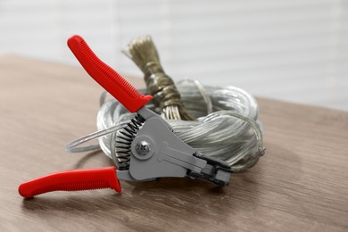Photo of Cutters and stripped wire on wooden table indoors, closeup