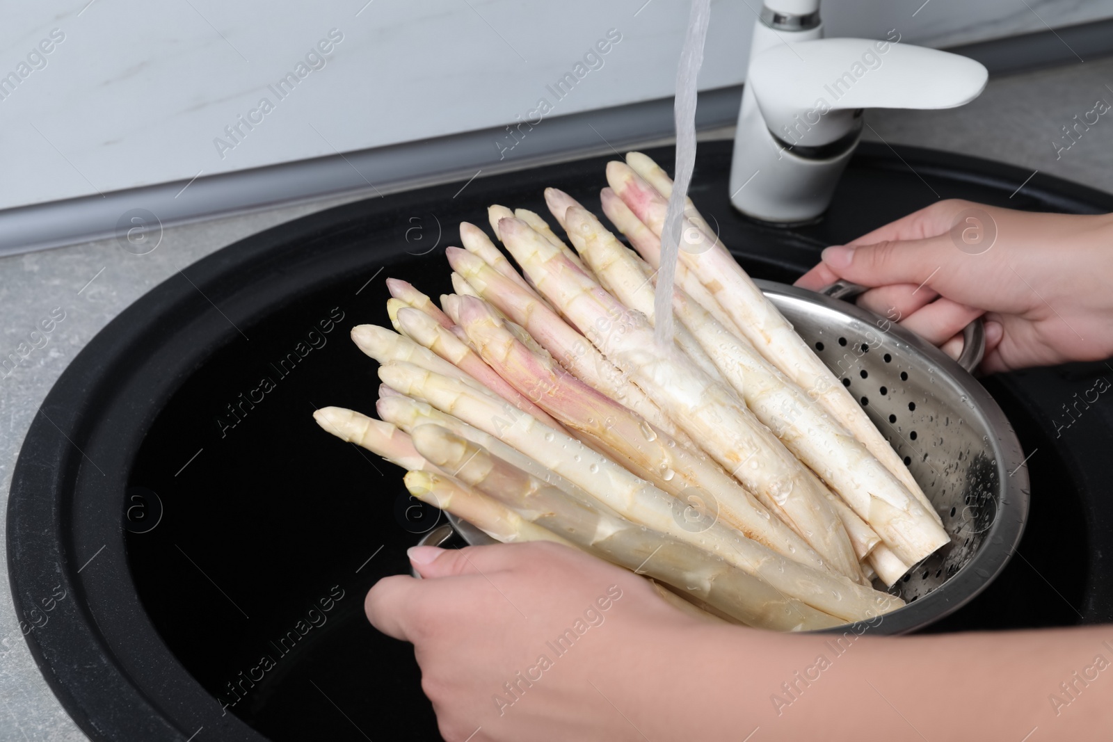 Photo of Woman washing fresh white asparagus over sink, closeup