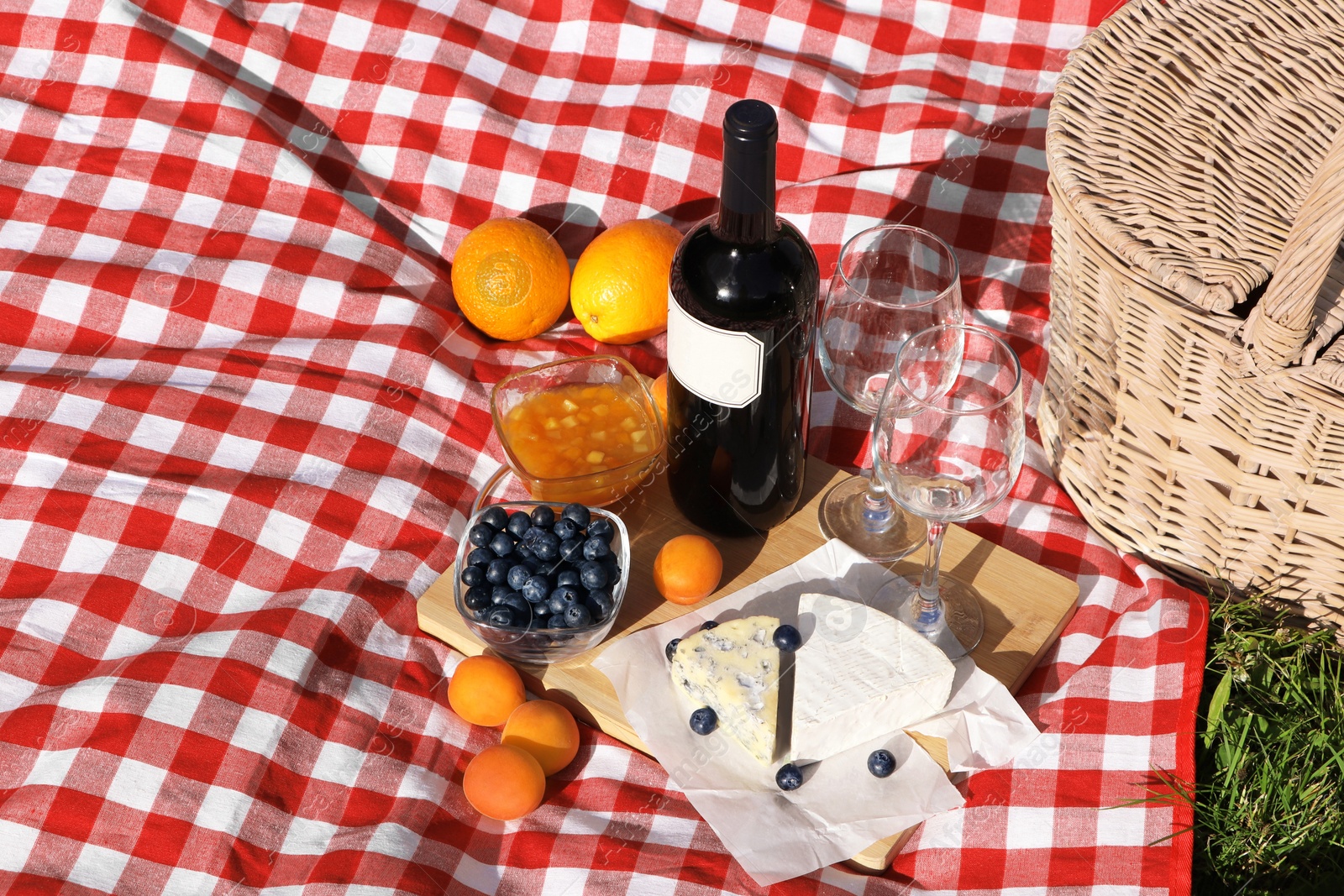 Photo of Picnic blanket with delicious food and wine outdoors on summer day