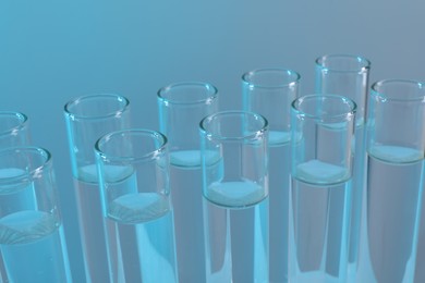 Laboratory analysis. Many glass test tubes on light blue background, closeup