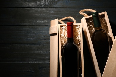 Photo of Crates with bottles of wine on wooden table, flat lay. Space for text