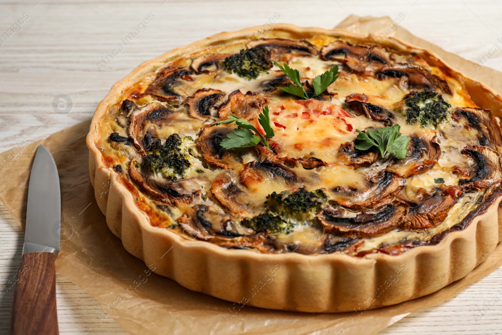 Photo of Delicious quiche with mushrooms and parsley on white wooden table, closeup
