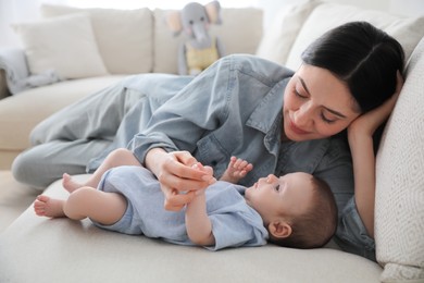 Young woman with her cute baby on sofa at home