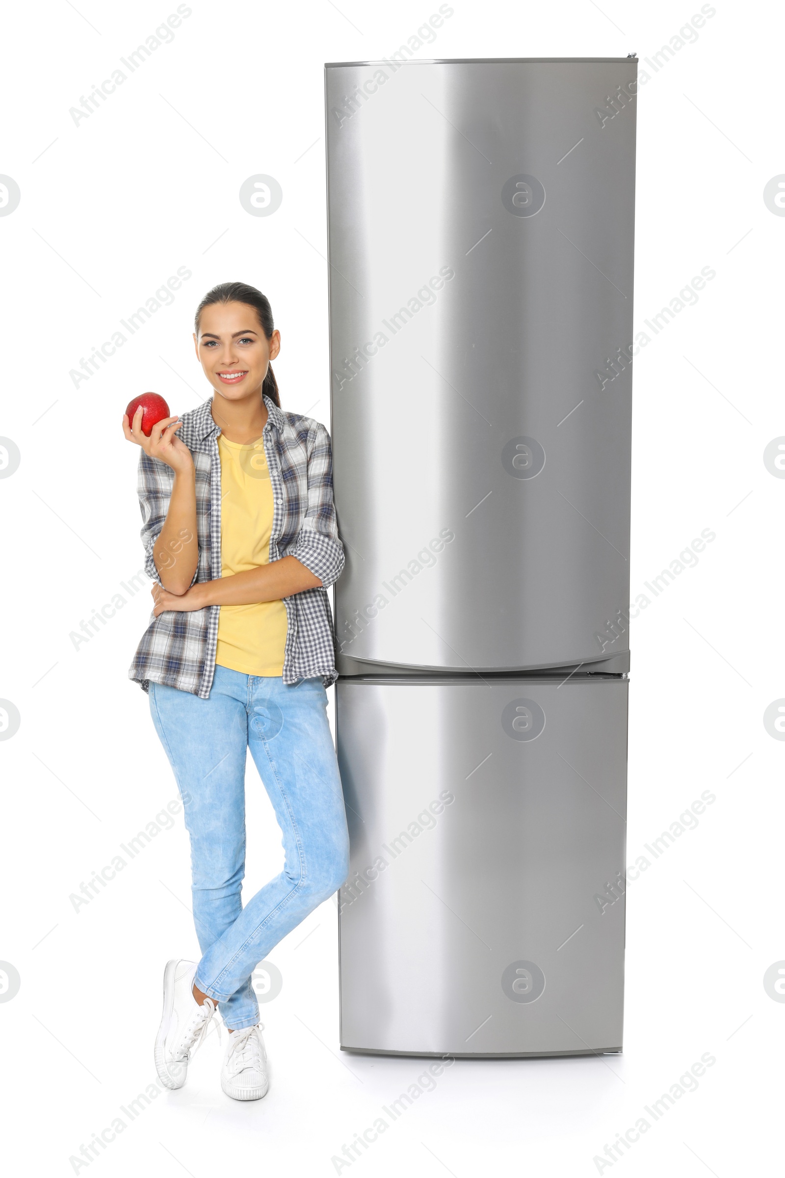 Photo of Young woman with apple near closed refrigerator on white background