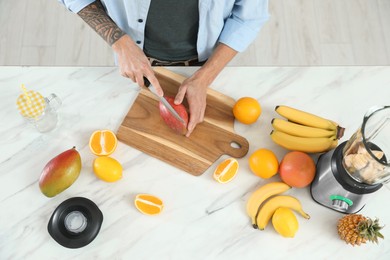 Man preparing ingredients for tasty smoothie at white marble table in kitchen, above view