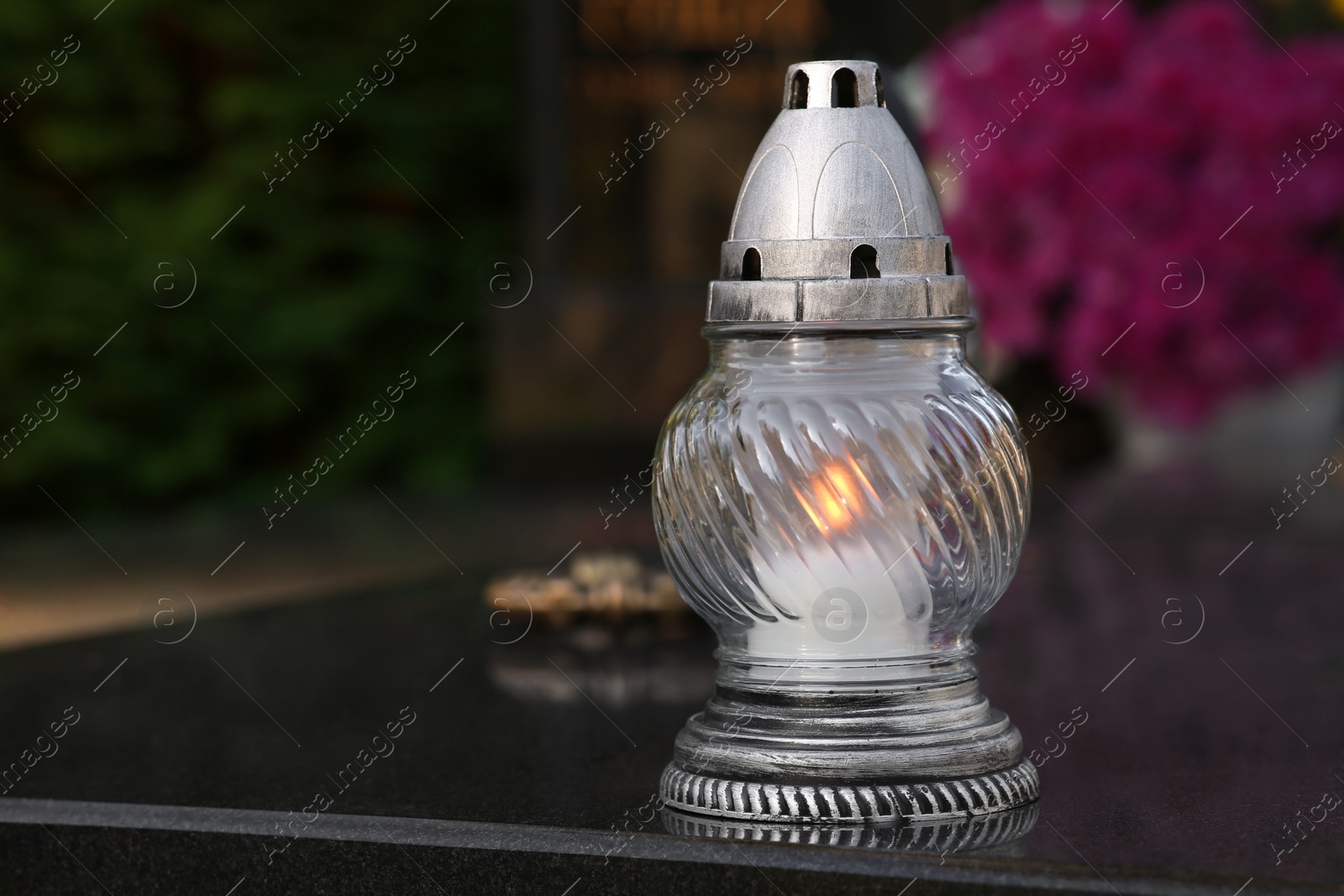 Photo of Grave lantern with burning candle on granite surface in cemetery, space for text