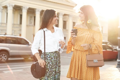 Photo of Young women with stylish bags on city street