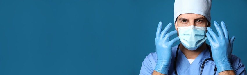 Image of Doctor in protective mask and medical gloves against blue background. Banner design with space for text 