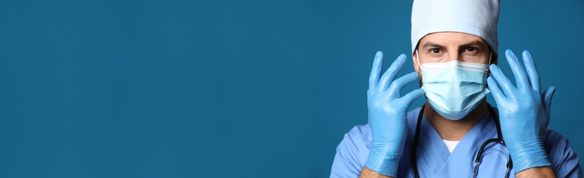 Doctor in protective mask and medical gloves against blue background. Banner design with space for text 