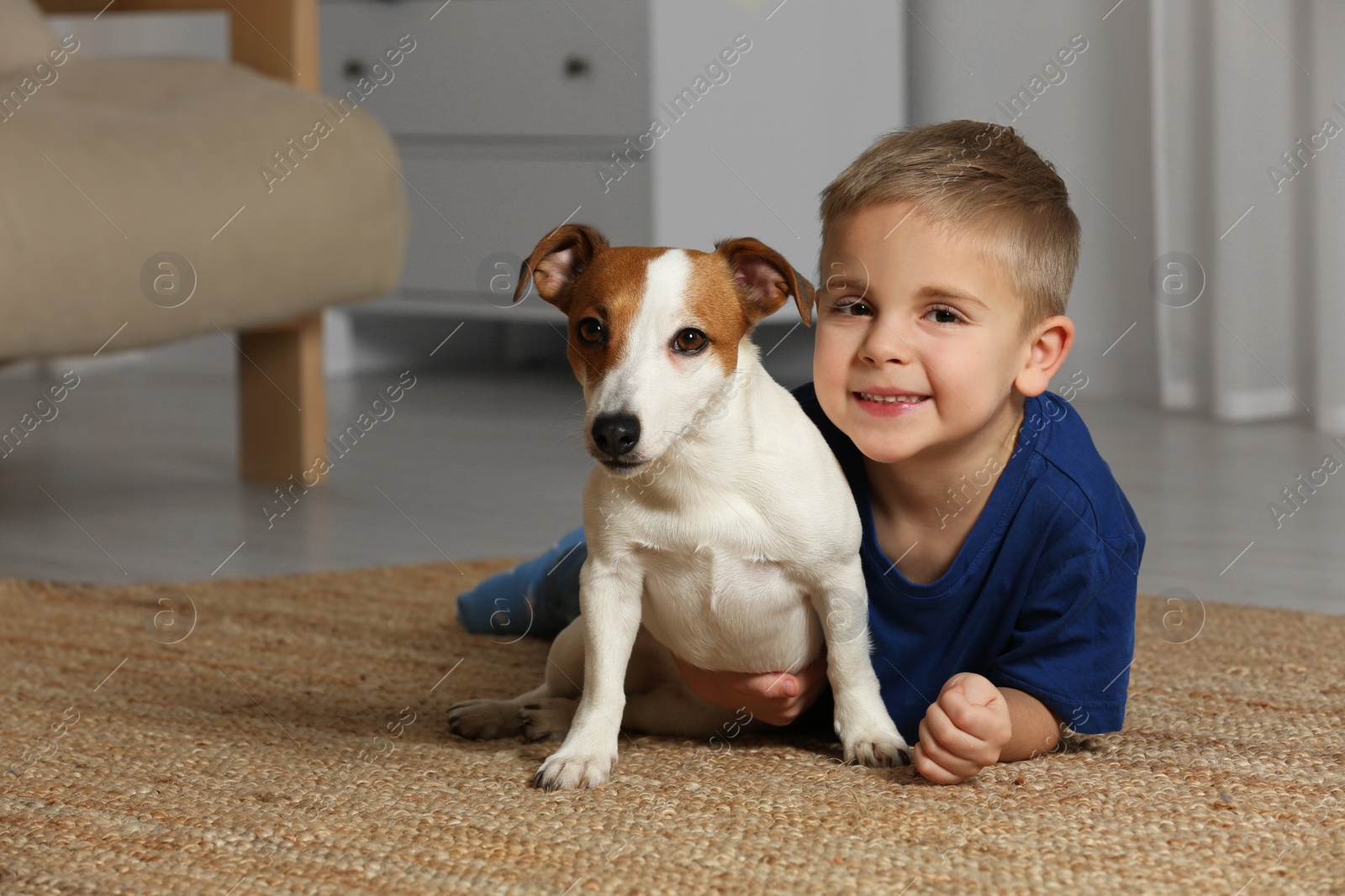 Photo of Little boy with his cute dog on floor at home, space for text. Adorable pet