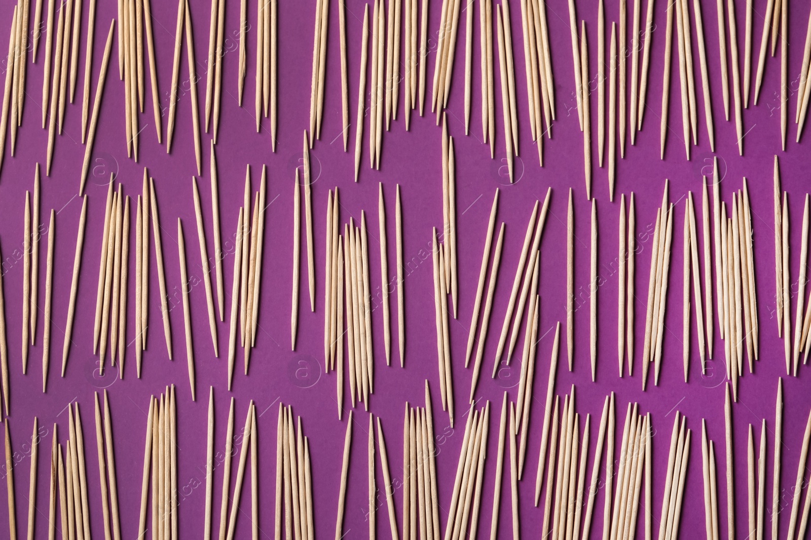 Photo of Wooden toothpicks on purple background, flat lay