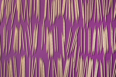 Photo of Wooden toothpicks on purple background, flat lay