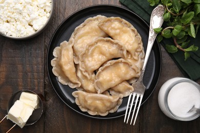 Delicious dumplings (varenyky) with cottage cheese served on wooden table, flat lay