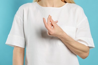 Photo of Woman snapping her fingers on turquoise background, closeup. Bad habit