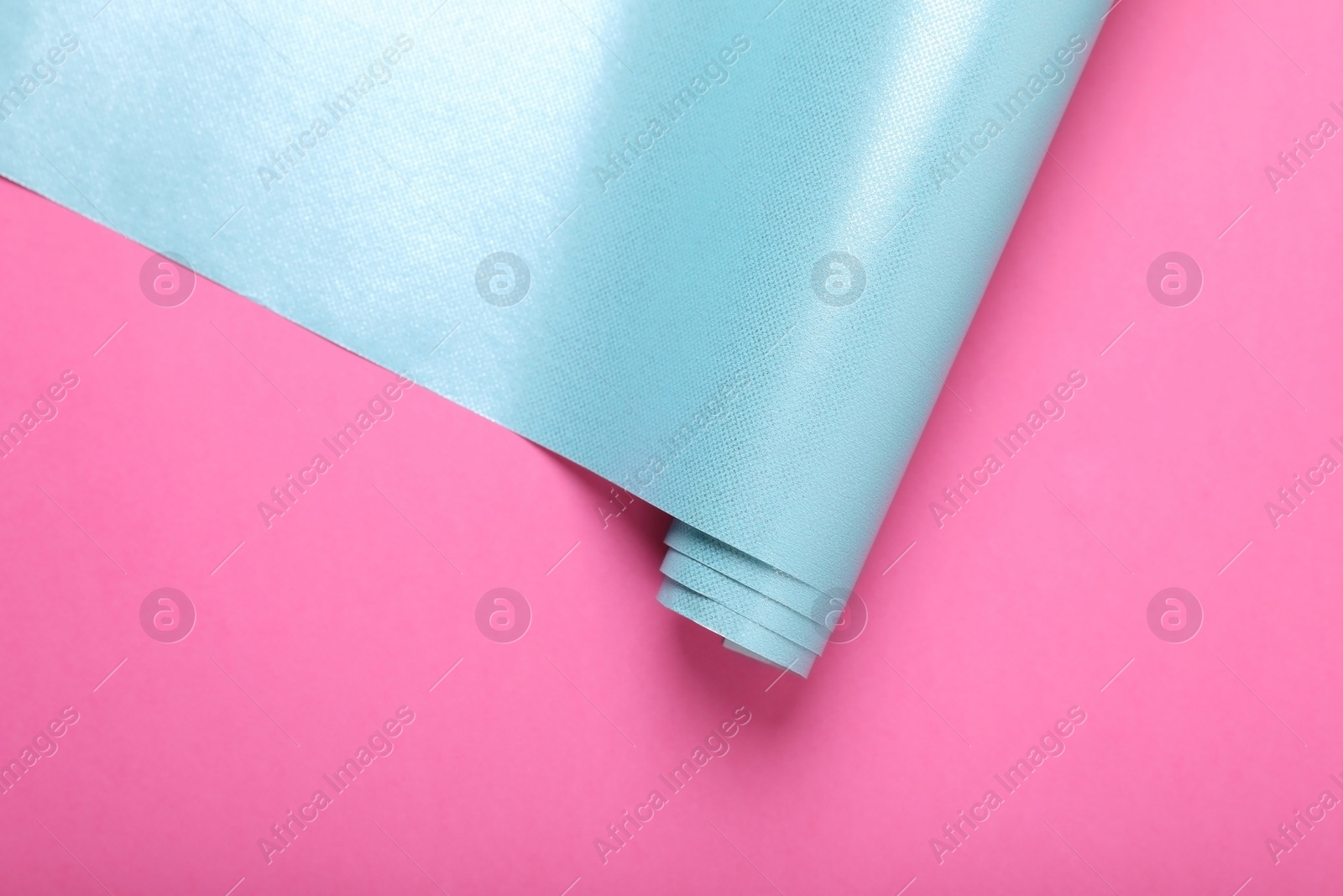 Photo of Roll of wrapping paper on pink background, top view