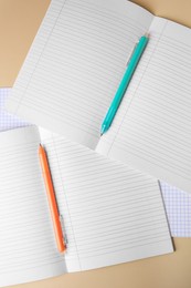 Photo of Copybooks with erasable pens on beige background, flat lay