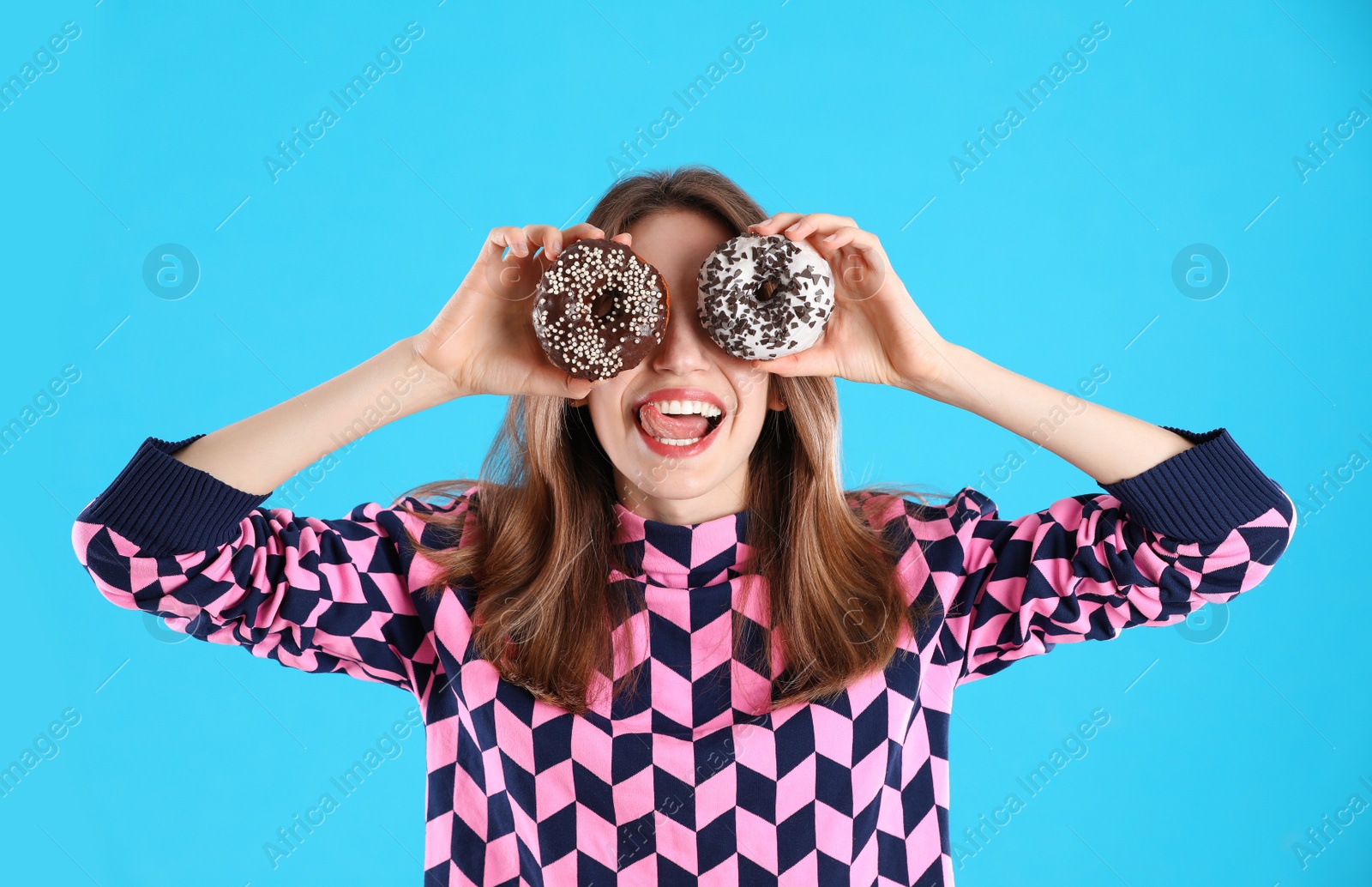 Photo of Beautiful young woman with donuts on light blue background