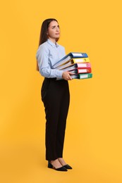 Disappointed woman with folders on orange background