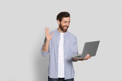 Emotional bearded man with laptop on light background