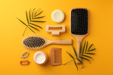 Photo of Flat lay composition with wooden brushes and different hair products on orange background