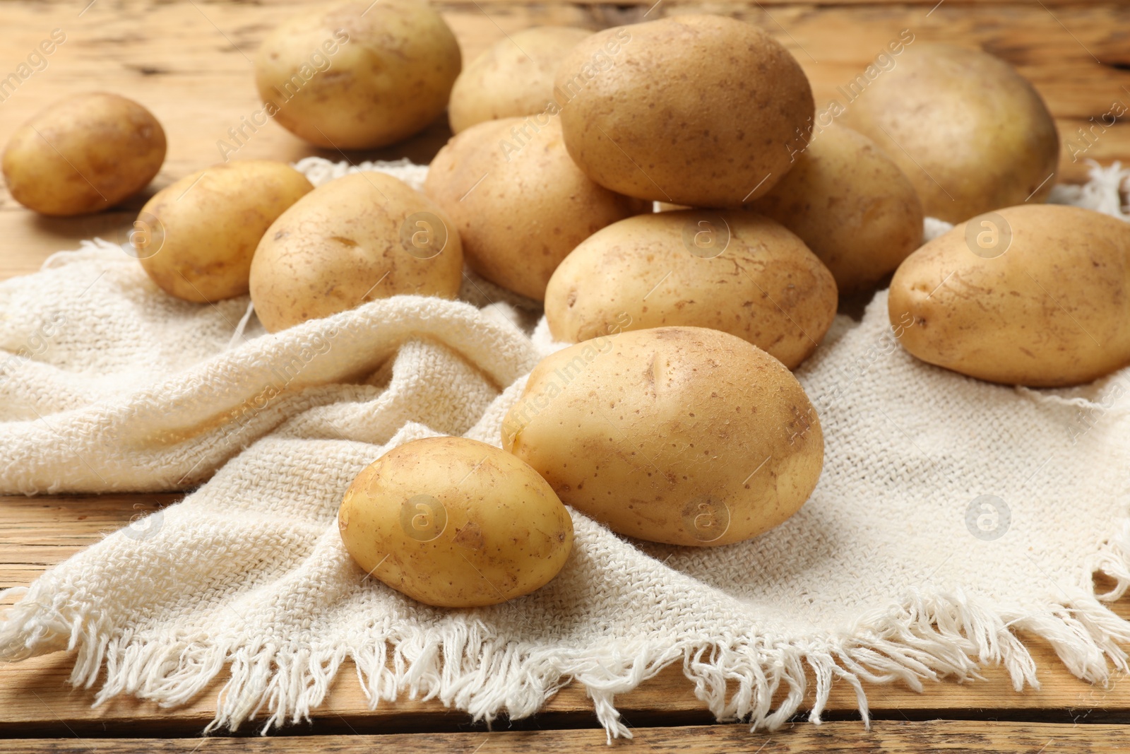 Photo of Raw fresh potatoes and napkin on wooden table