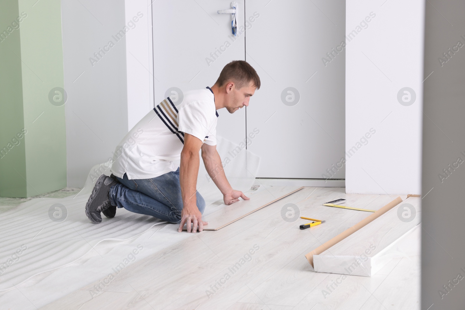 Photo of Man installing new laminate flooring in room