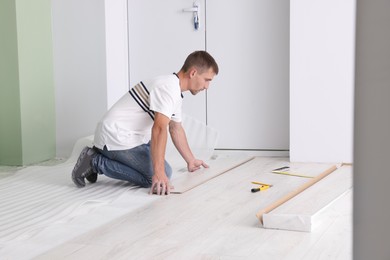 Photo of Man installing new laminate flooring in room