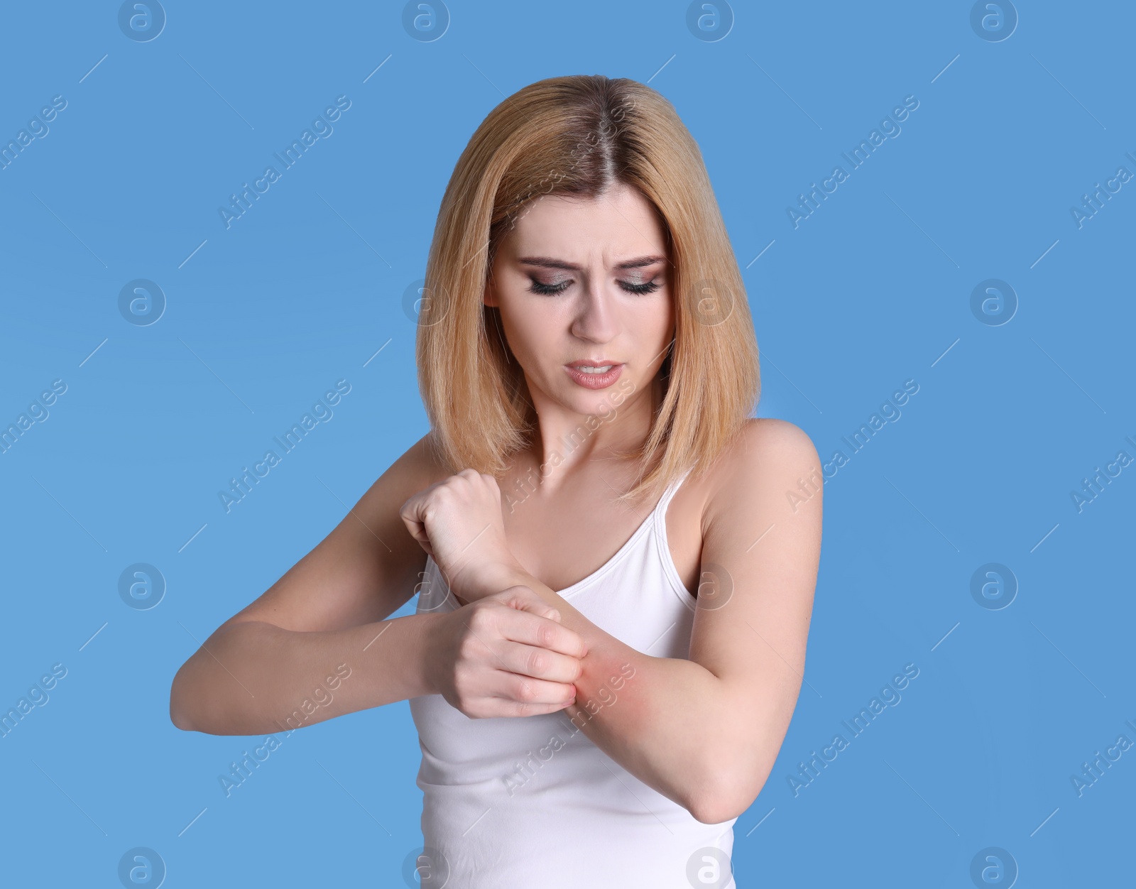 Photo of Woman with allergy symptoms scratching forearm on color background