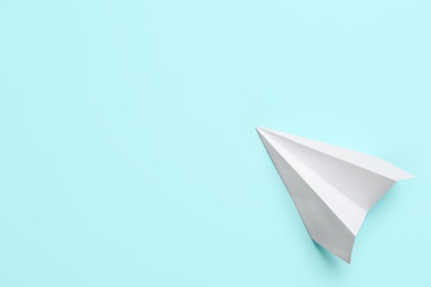 Photo of White paper plane on light blue background, top view. Space for text