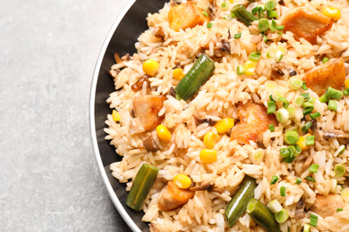 Photo of Delicious rice pilaf with chicken and vegetables on light grey table, closeup
