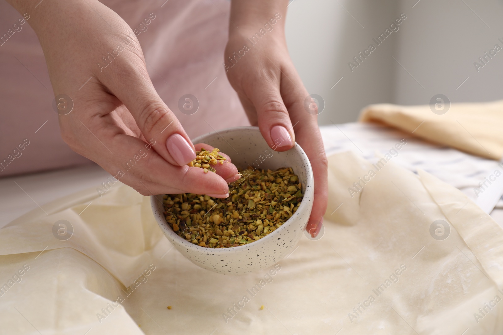 Photo of Woman putting filling into baking dish with dough to prepare baklava, closeup